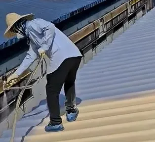 APTECH Foam and Coat spray construction scene — worker applying Spray PU Foam and Polyurea on inclined metal roof