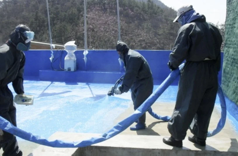 Workers applying blue polyurea waterproofing spray coating on rooftop — APTECH industrial waterproofing