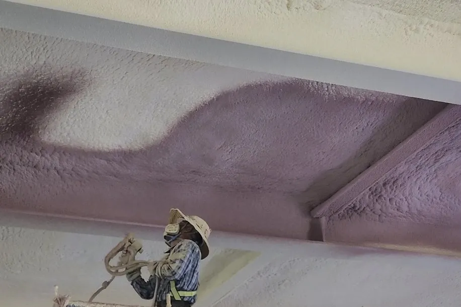 Worker applying spray PU foam insulation on industrial wall surface — APTECH polyurethane foam insulation